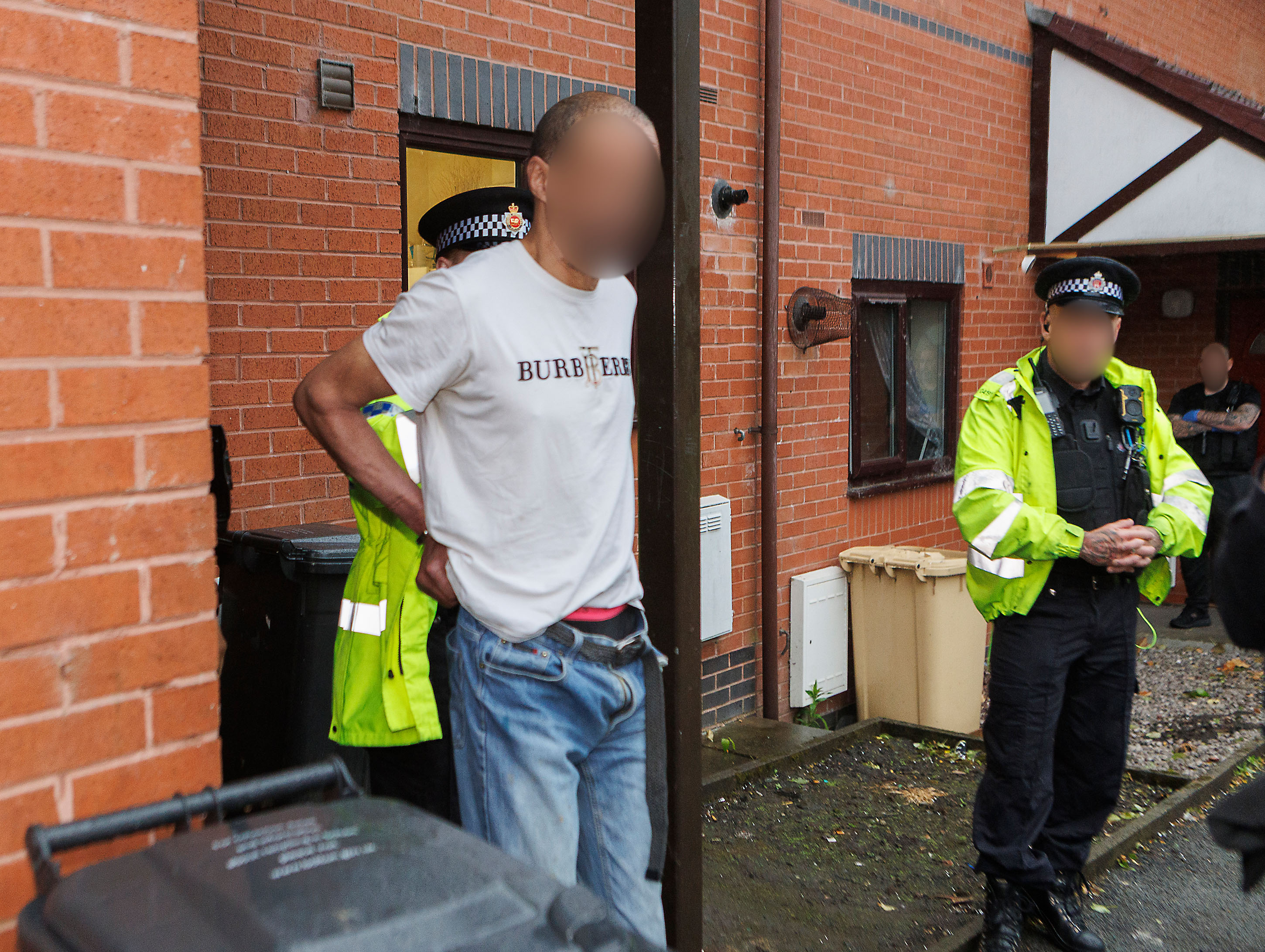 Image of arrested man being taken towards a GMP custody van.
